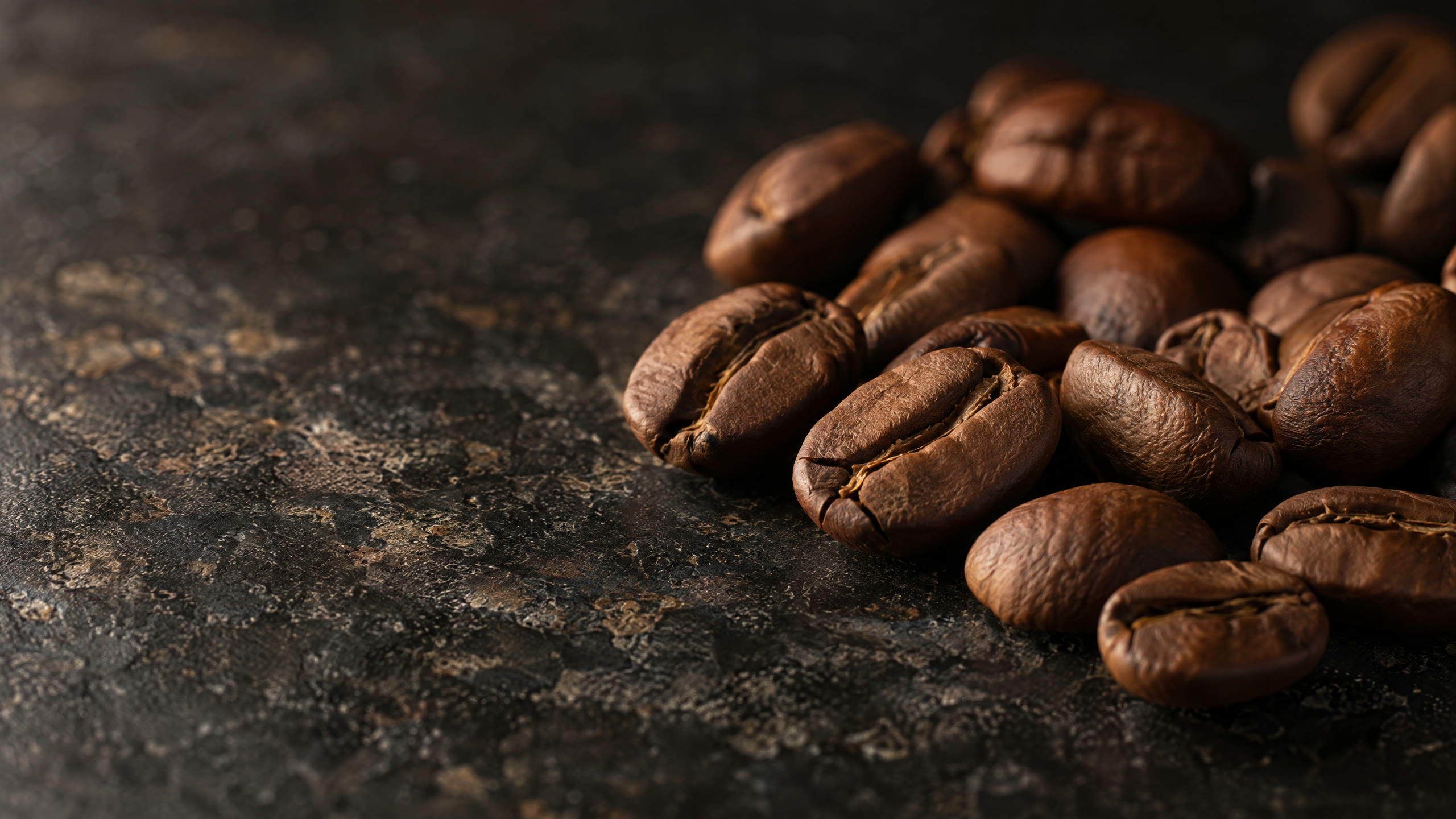 Whole roasted coffee beans on dark stone