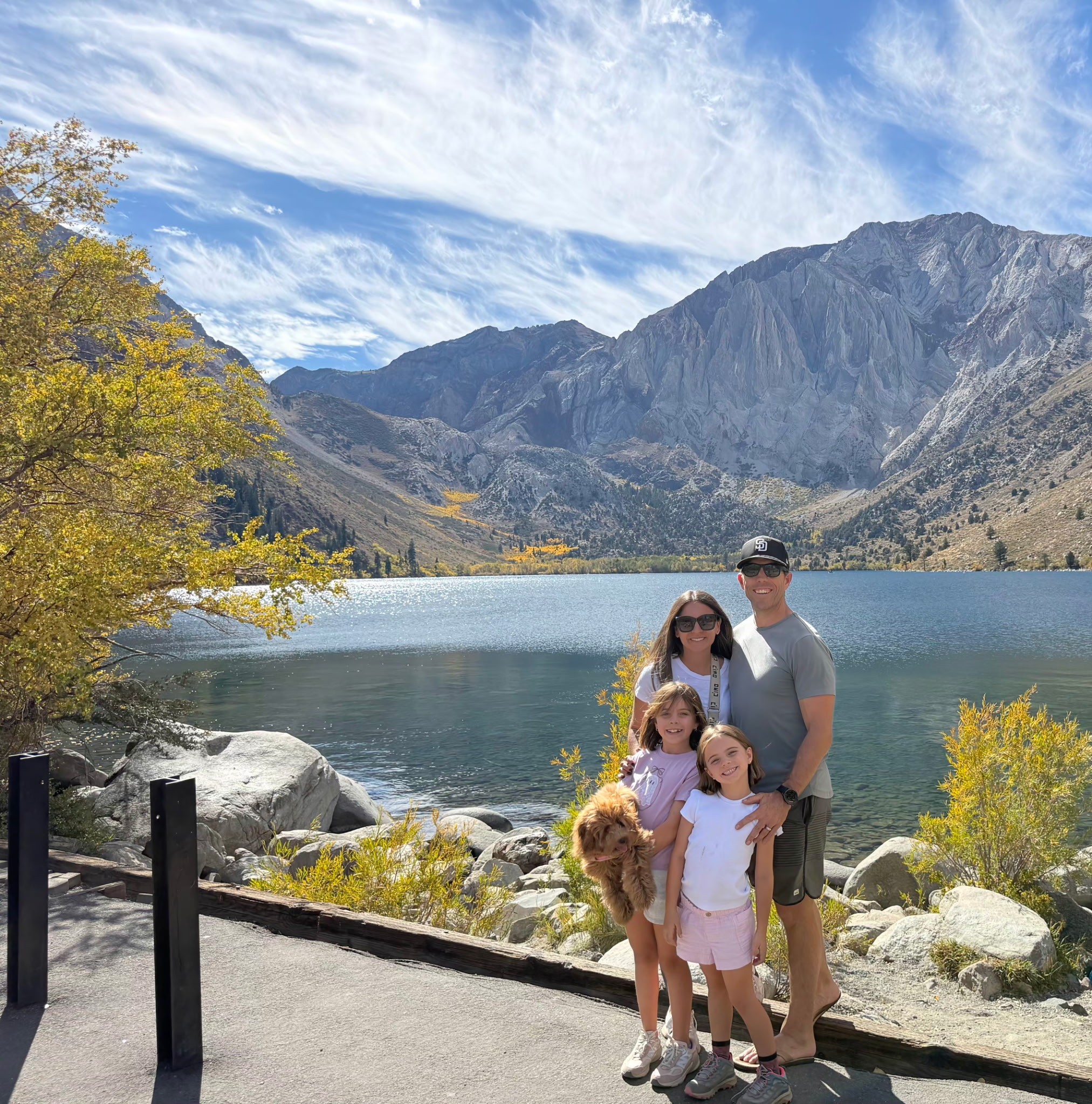 Alyssa and Brian with their two daughters and their dog beside a mountain lake